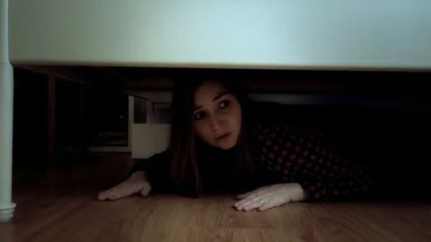 A woman hides under the bed to keep an eye on her husband
